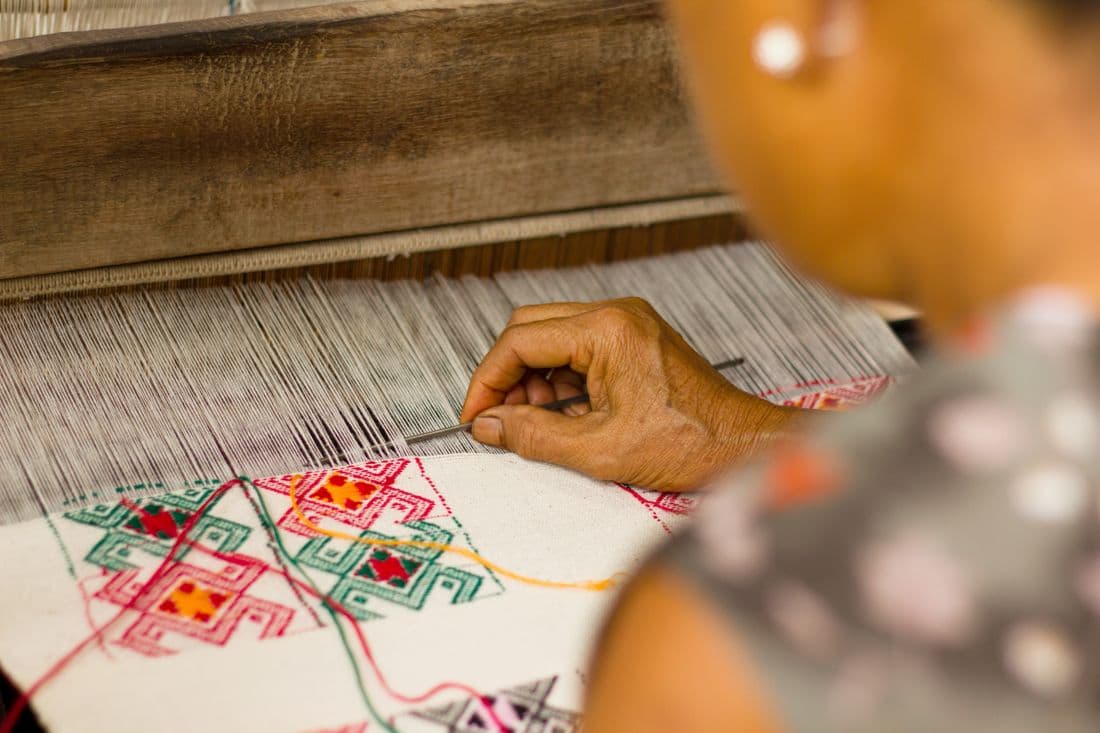 Artisan hands weaving zari on a Banarasi loom